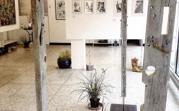 An exhibition installation of weathered wooden sculptures and photograps