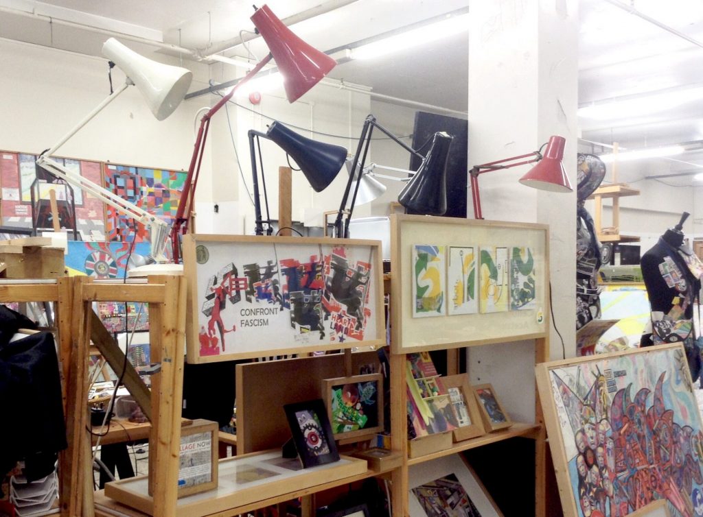 a studio with colourful angle lamps and collage artworks one has the text "CONFRONT FASCISM"