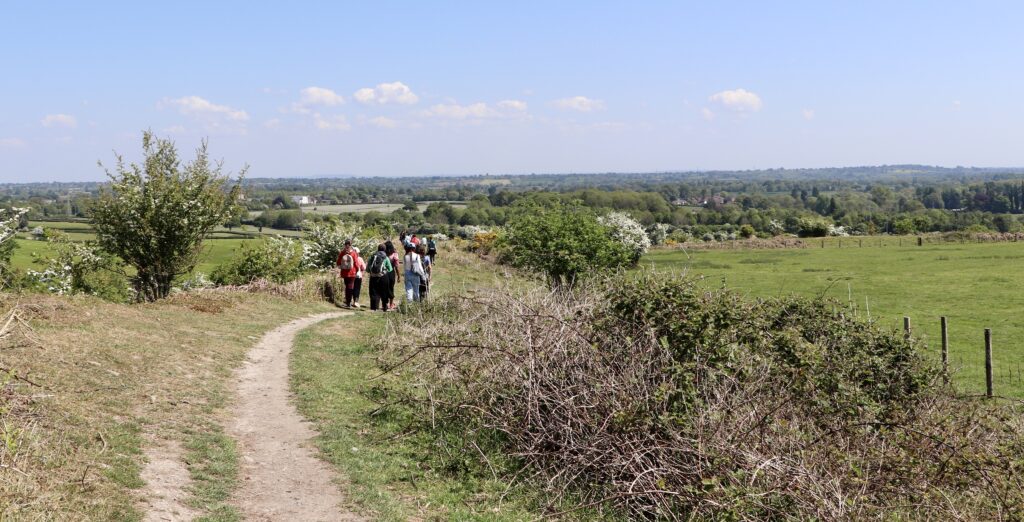 People walking along a path up on the hill fort with a view arising in the distance