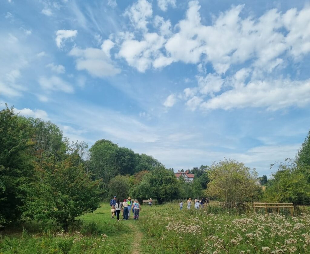 A group of people walk along a path in greenfields under a blue cloudy sky
