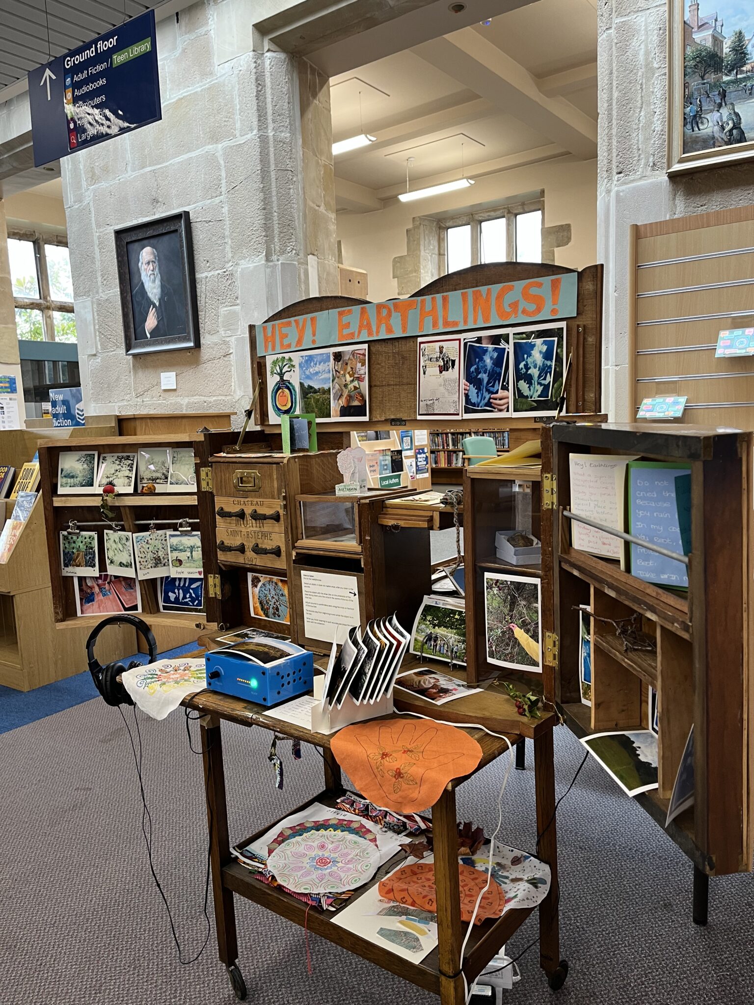 A wooden cabinet with open doors, drawers and spaces to explore containing various artworks and natural objects.